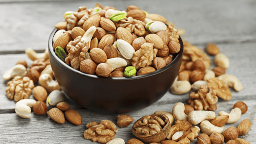 A big bowl filled and overflowing with different types of nutritional nuts and seeds