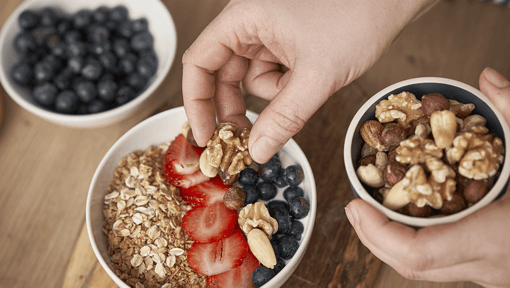 someone adding walnuts to a healthy yogurt parfait 