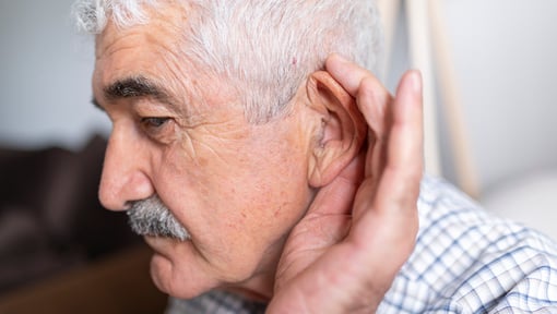 Older adult man cupping his ear to hear better