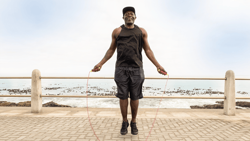 Older adult man doing a high intensity interval workout outside near the ocean