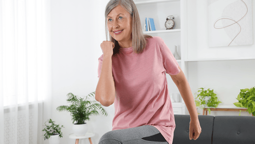 A older woman doing a versatile HIIT workout in her home