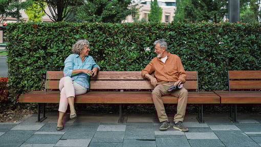 Two older adults enjoying a chat on a park bench