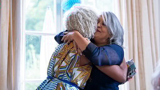 Two women warmly embracing in a bright indoor setting, conveying a sense of gratitude and connection.