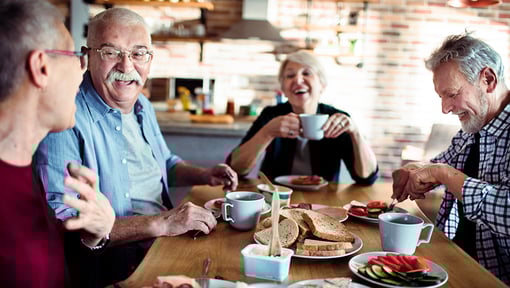 A group of older adults sitting around a wooden table enjoying a meal together