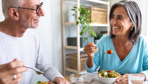 A older adult man and woman sitting at their kitchen table having a nutrient dense meal