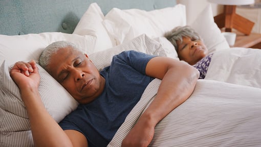Two senior aged adults sleeping in bed after a night of good sleep.