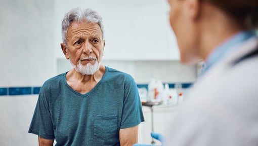 An older adult speaking with a healthcare professional in a clinical setting