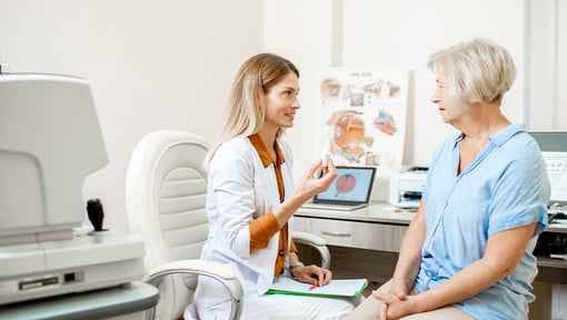 Eye doctor consulting with a patient in an exam room, using visual aids to explain eye health and treatment options.