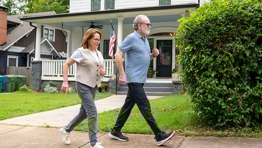 A pair of walkers engaged in interval walking along a neighborhood street, demonstrating a mix of fast and steady walking for exercise.