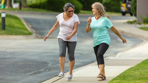 Two older adult women enjoying each others company during an interval training walk