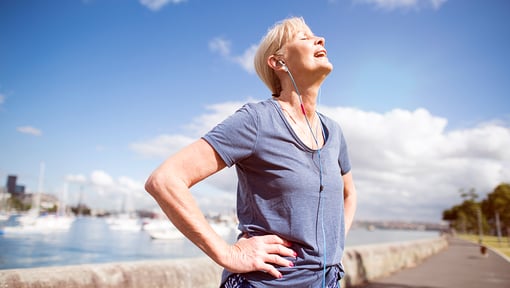 A woman standing on a walking path enjoying a moment in the sun after doing an interval walking workout