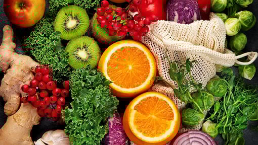 Variety of fresh fruits and vegetables commonly associated with vitamins and minerals, including citrus, kiwi, red peppers, leafy greens, and berries