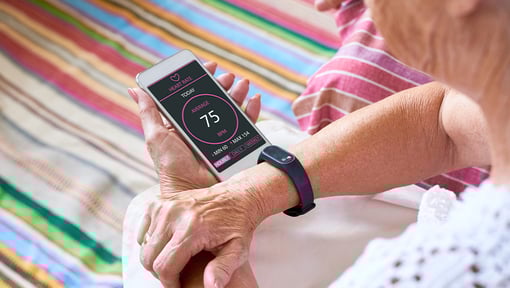 A older adult woman is syncing her fitness watch with her fitness app on her smart phone. 