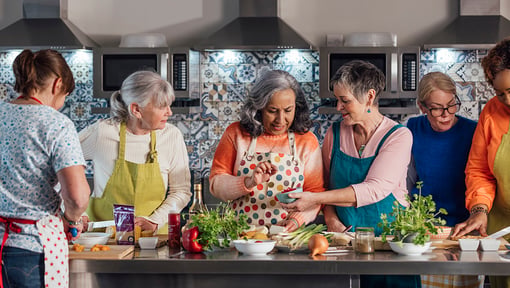 older adults gathered around a island during a cooking class 