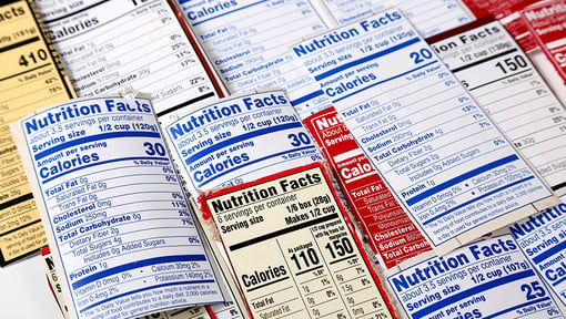 a bunch of different nutrition fact labels laying out and overlapping on a tabletop. 