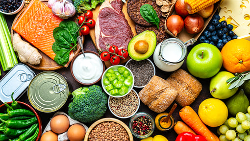 Selection of nutrient‑rich foods such as salmon, avocado, berries, broccoli, carrots, eggs, whole‑grain bread, beans, and fresh produce displayed together.