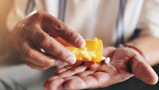Prescription medication being dispensed from a pill bottle into a person's hand, illustrating medication use and management.
