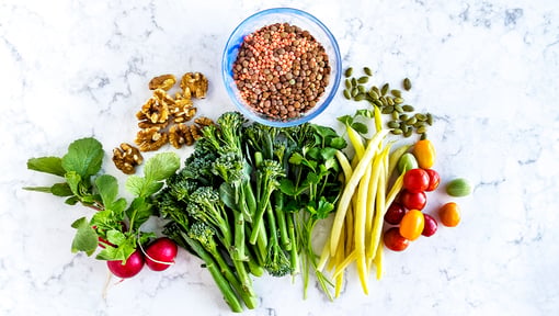 High-fiber plant foods including lentils, leafy greens, broccoli, nuts, seeds, and vegetables displayed for healthy eating and gut health.