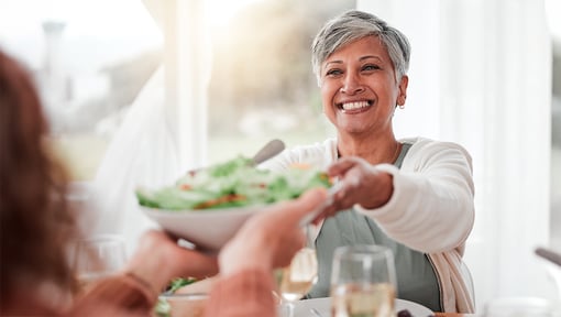Older adult smiling while holding a bowl of fresh salad, highlighting healthy eating habits that support gut health.