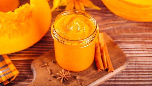 Pumpkin purée and pumpkin wedges on a wooden surface.