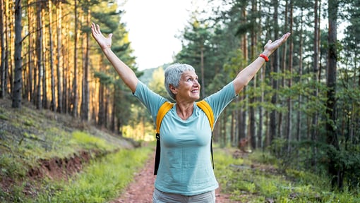 Older adult enjoying an outdoor hike on a forest trail.