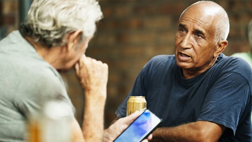 Two older adults seated across from each other and engaged in active listening conversation.